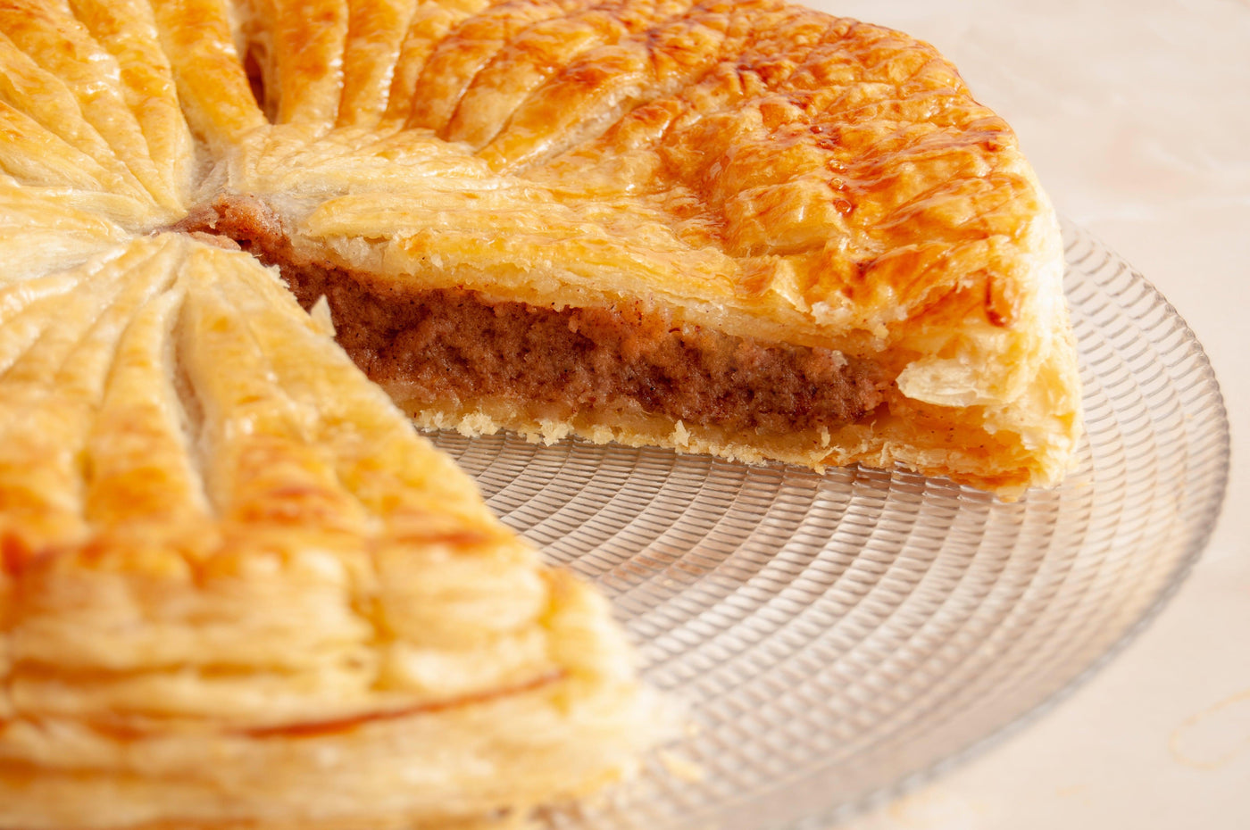 Gâteau Pithiviers coupé en portions, révélant sa garniture d'amande riche et sa pâte feuilletée dorée.