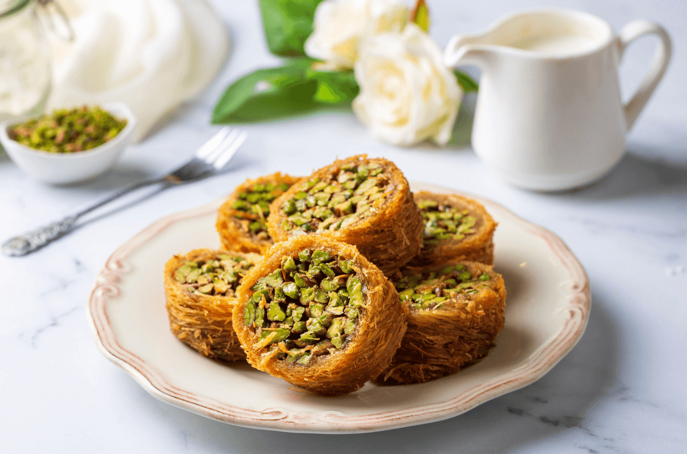 Assiette de kadaïf doré, dessert moyen-oriental aux fils de pâte et noix.